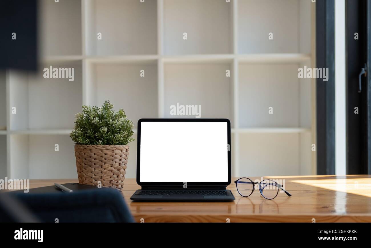 Mock up of blank screen tablet with keyboard on wooden desk at home office Stock Photo