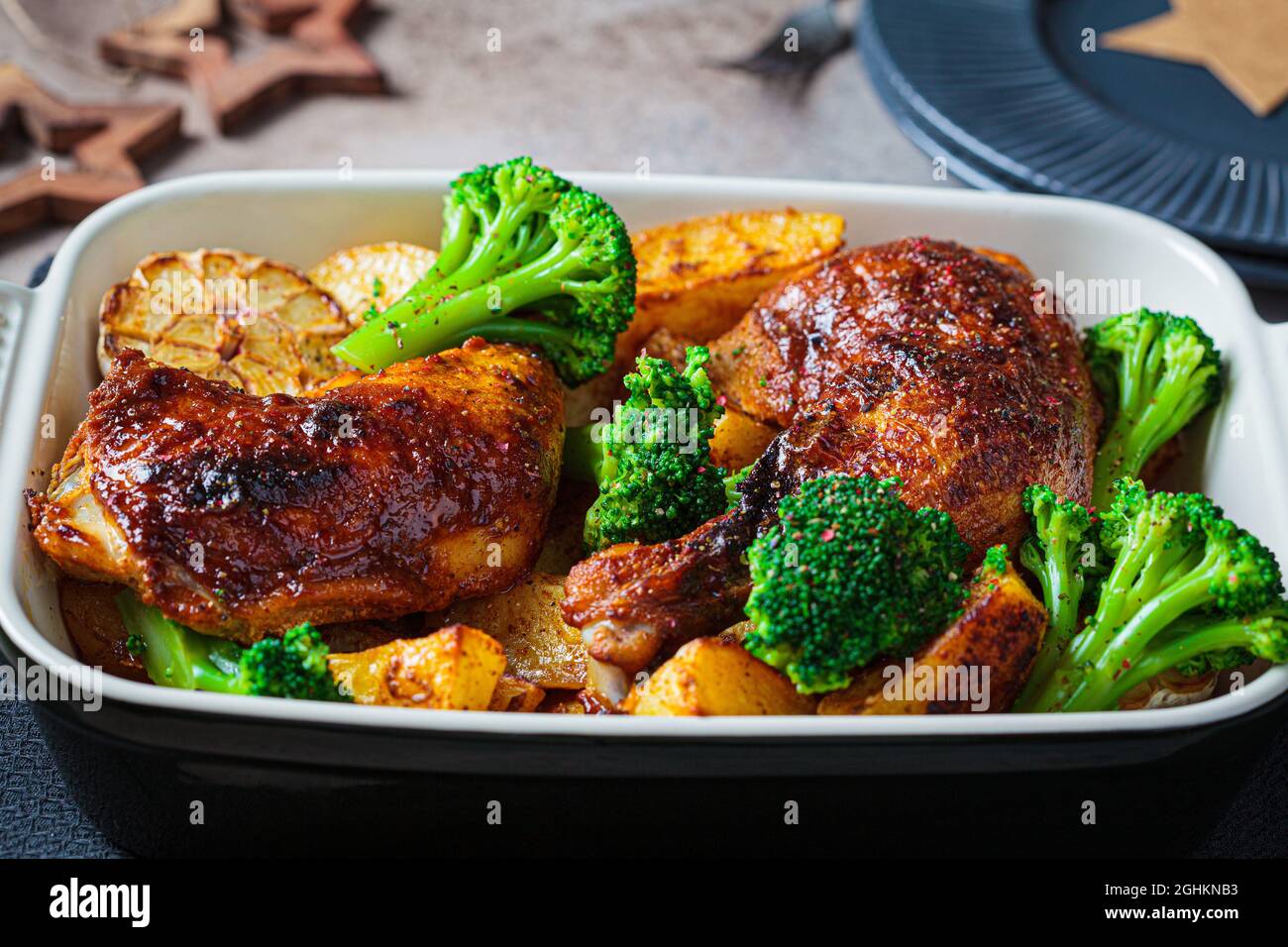 Oven baked chicken legs with potatoes, broccoli and garlic in baking