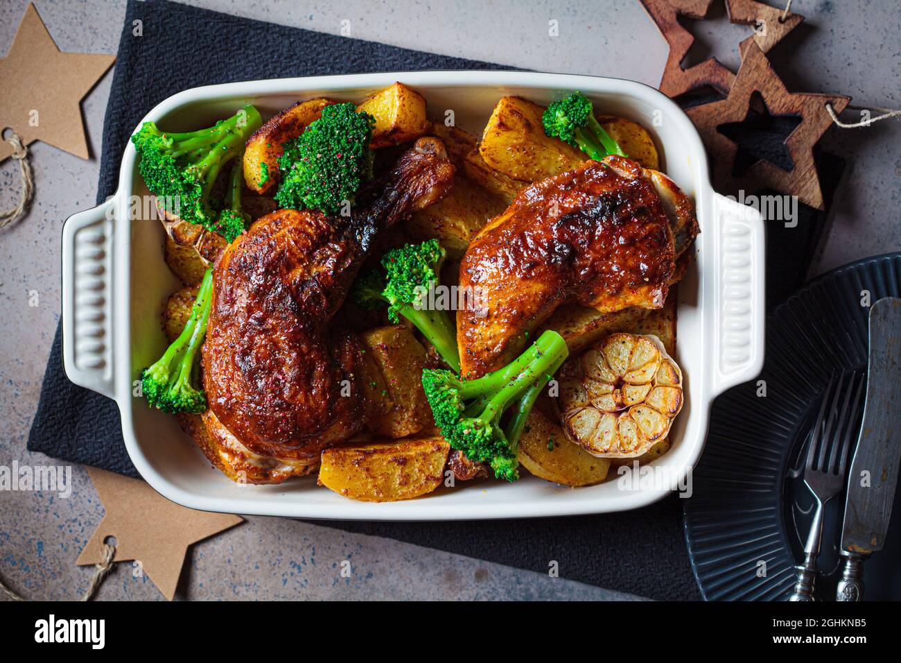 Oven baked chicken legs with potatoes, broccoli and garlic in baking