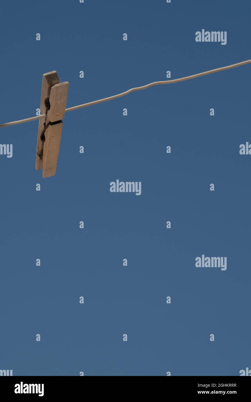 View of a single clothespin hanging on a rope against a blue sky Stock Photo