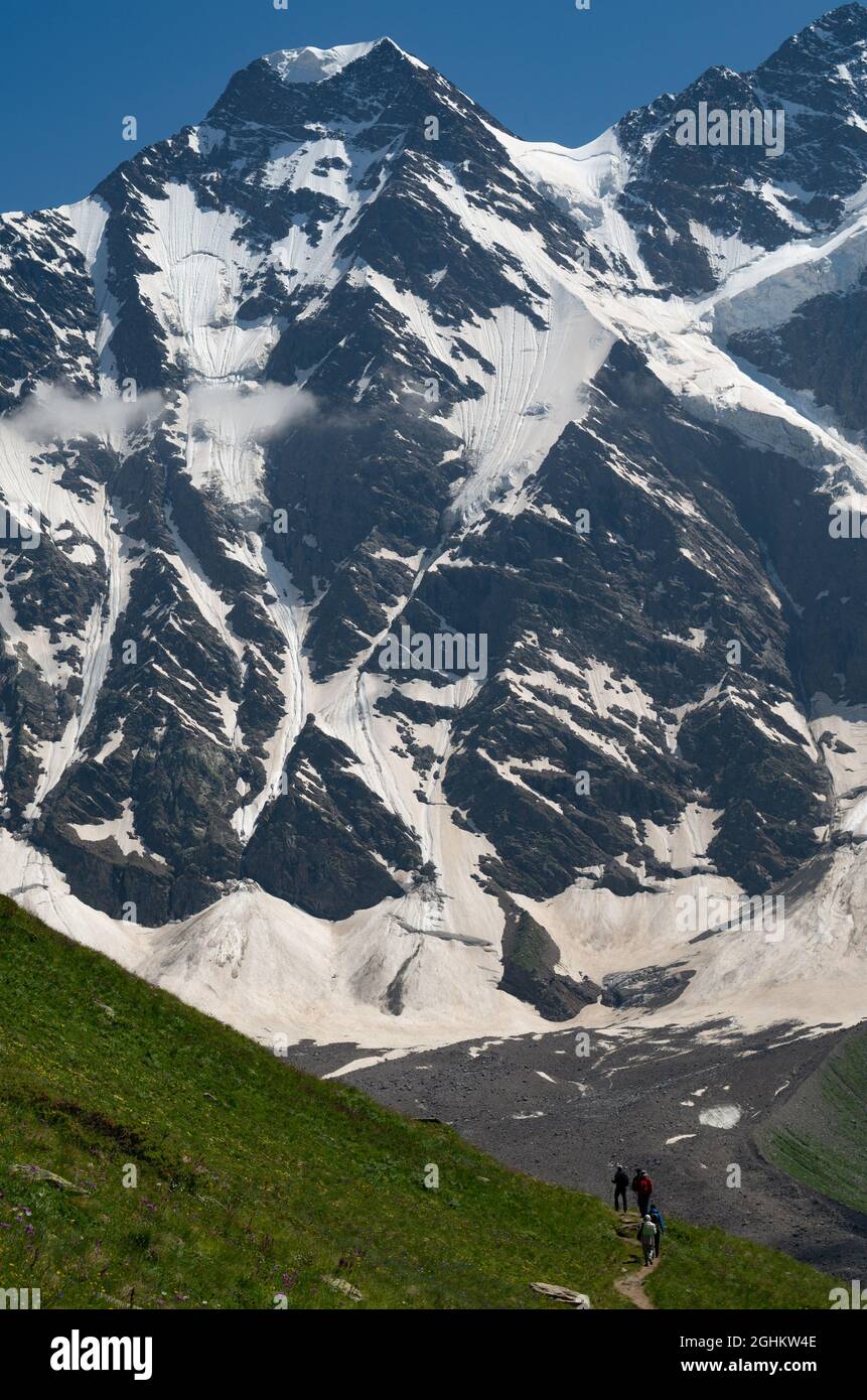 A group of hikers with backpacks are walking along a mountain range ...