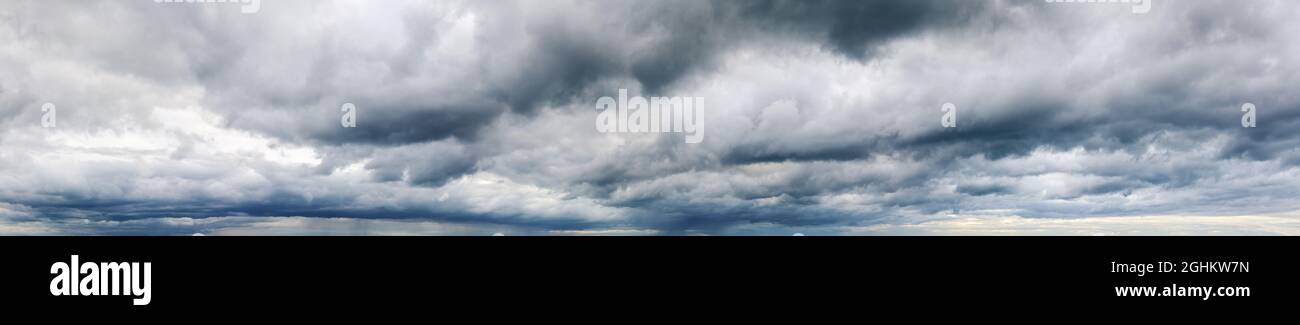 Stormy cloudy sky wide panorama, dramatic dark blue thunderclouds, gale cloudscape, gray cumulus rain clouds panoramic view, thunderstorm heaven Stock Photo