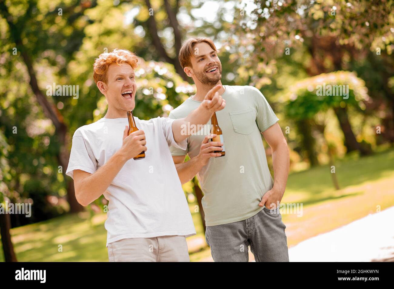 Two friends with beer having fun in park Stock Photo - Alamy