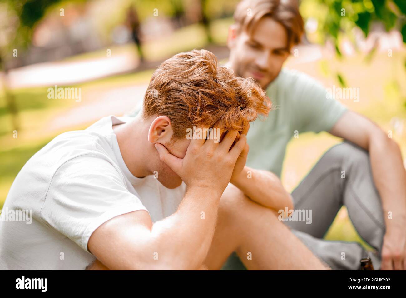 Guy hiding his face behind hands and friend Stock Photo
