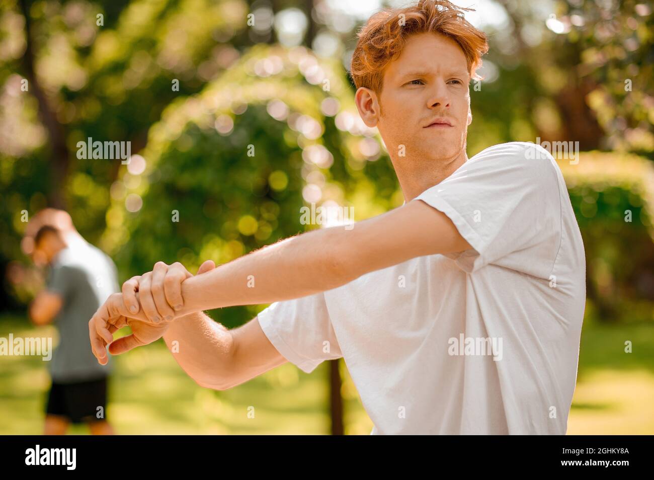 Guy doing warm-up in park on summer day Stock Photo
