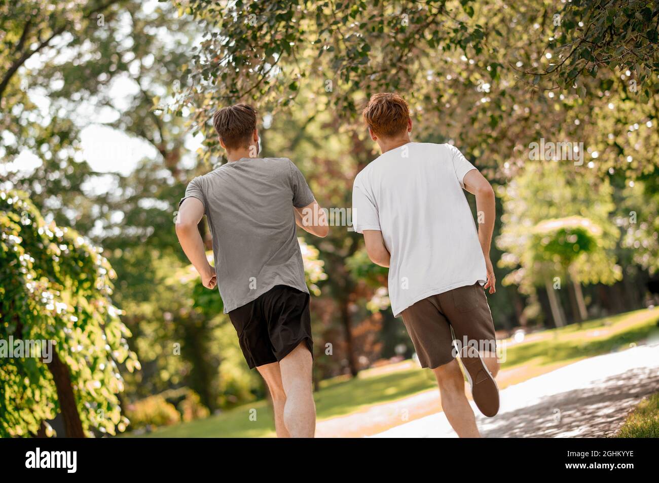 Guys running in park with backs to camera Stock Photo - Alamy