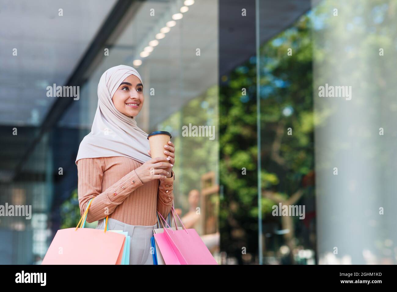 Cheerful pretty millennial muslim lady in hijab enjoy shopping with many packets with purchases Stock Photo