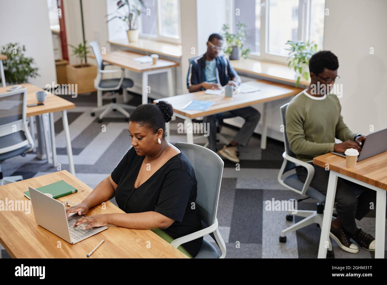 Serious Black businesswoman renting desk in open space coworking center Stock Photo