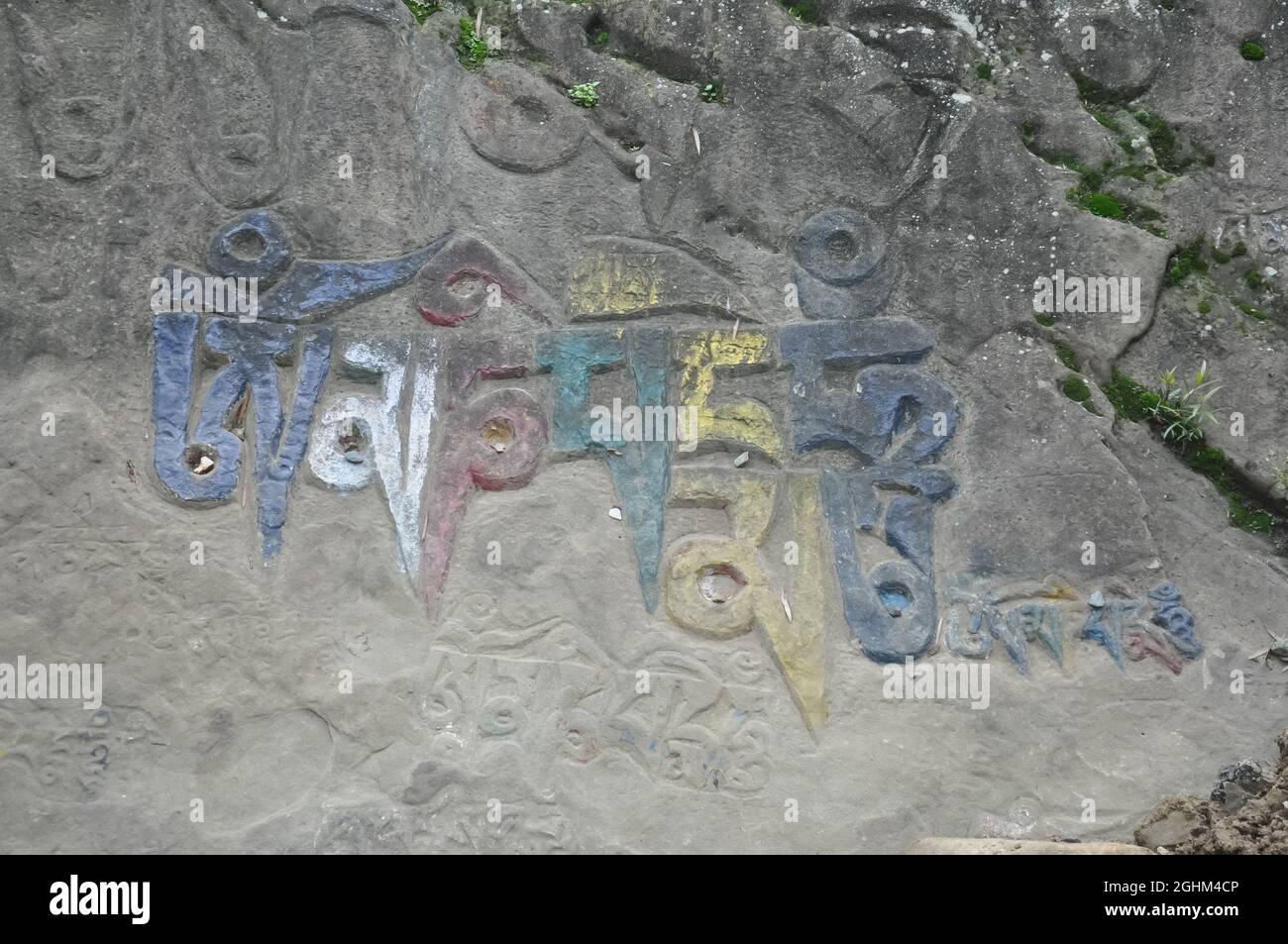 Om Mani Padme Hum (Buddhist mantra) written Tibetan script on rock in Rewalsar lake (Tso Pema), Himachal Pradesh, India Stock Photo