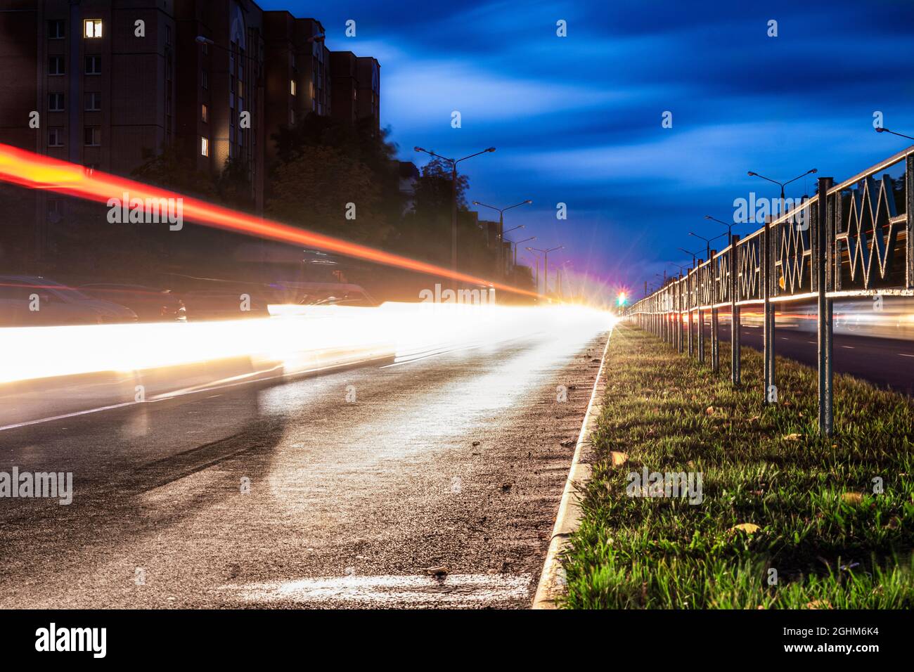 Night city road long exposure shot. The green grass with a dividing line recedes into the distance Stock Photo