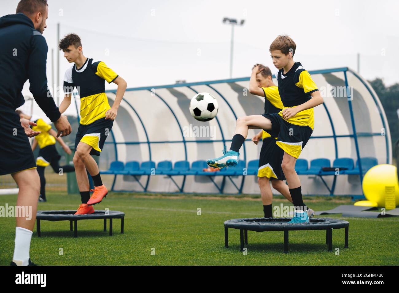 Football Club Players on Training Unit. Boys Running Fast on Soccer Practice. Coach Coaching Youth Football Team. Players Kicking Balls and Standing o Stock Photo