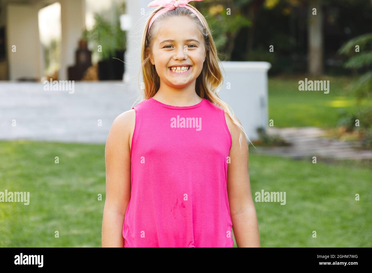 Portrait of smiling caucasian girl outside house looking at camera in garden Stock Photo