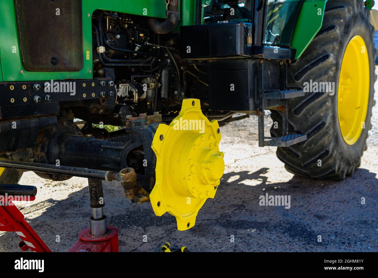 Green and yellow tractor without wheel to repair Stock Photo Alamy