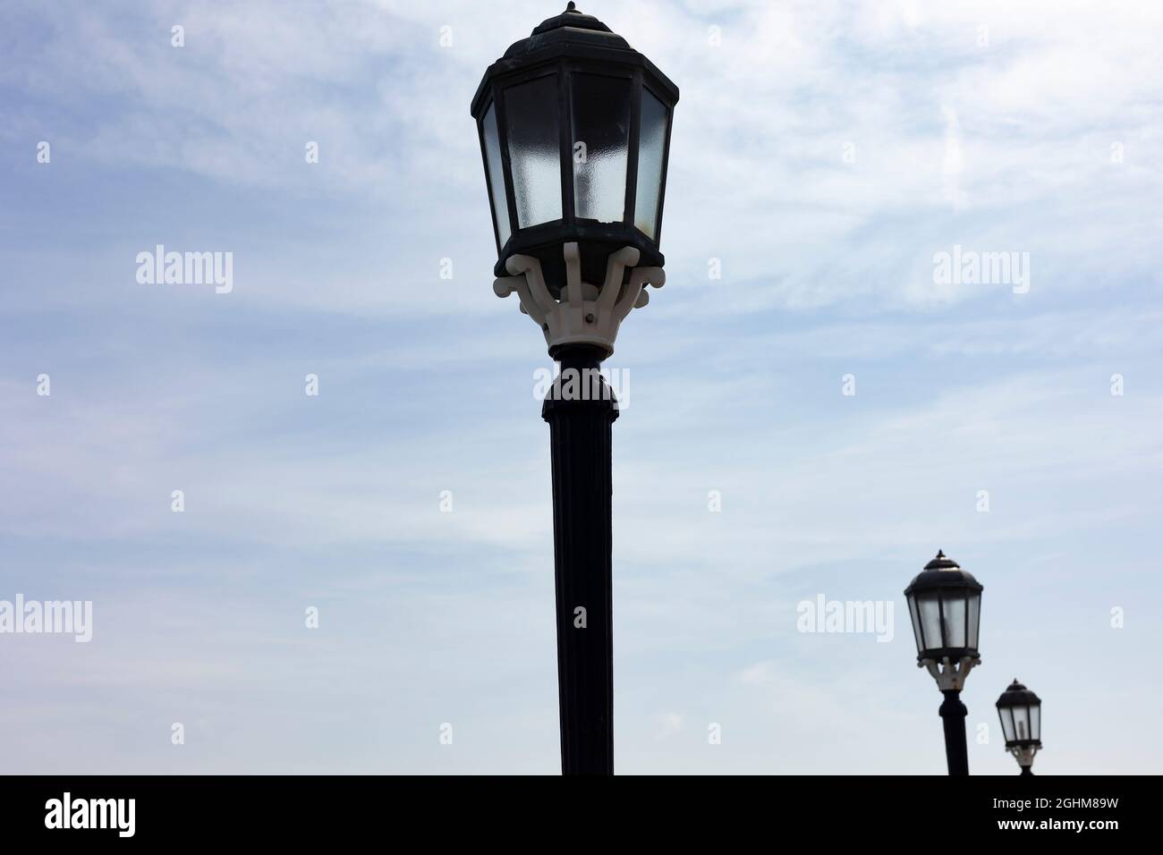looking up at three unlit lamp posts during the day, in Worthing, West Sussex, UK Stock Photo