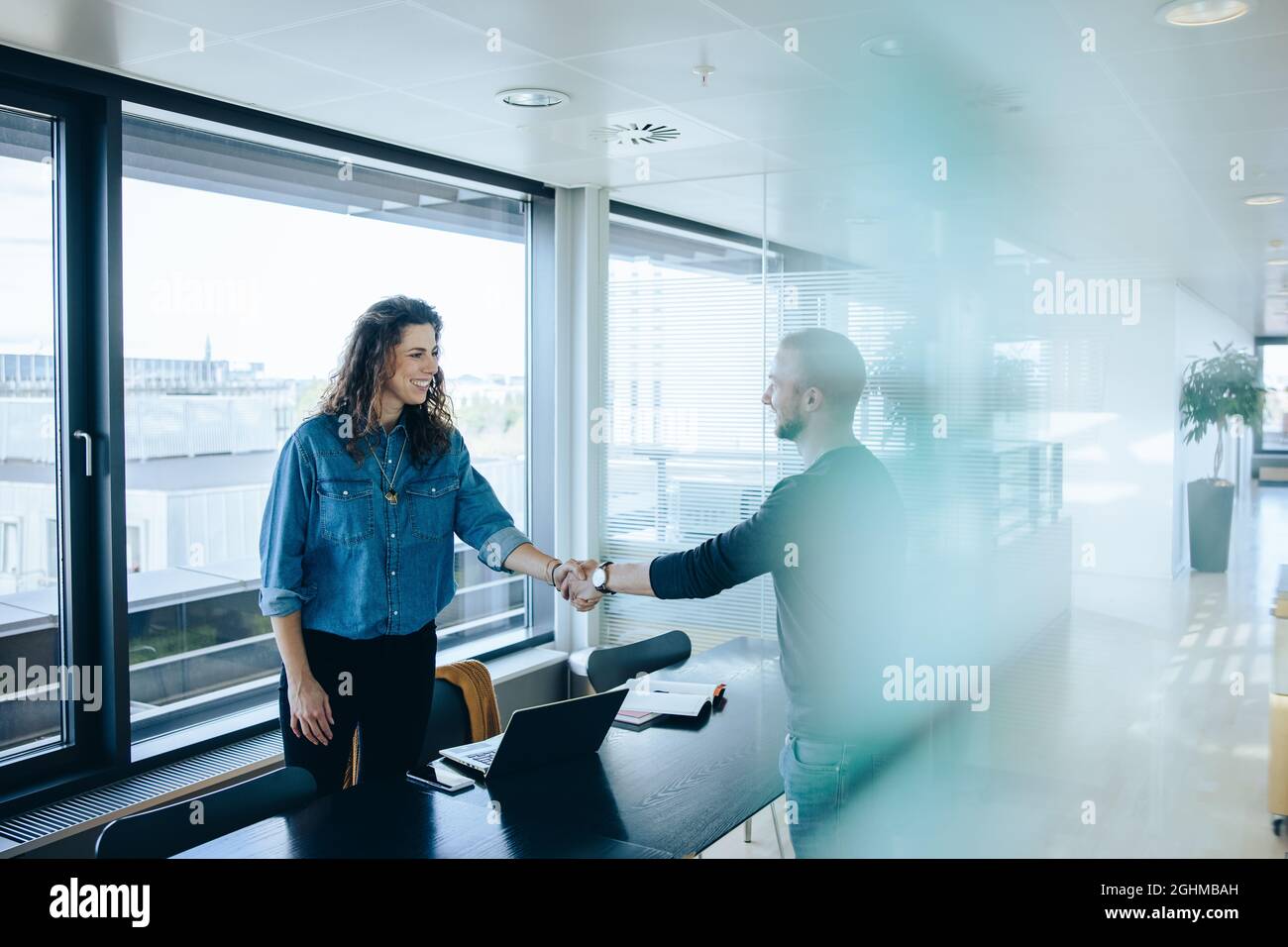 Employer shaking hand with man after successful job interview. businesswoman congratulating and shaking hands with job applicant in office boardroom. Stock Photo
