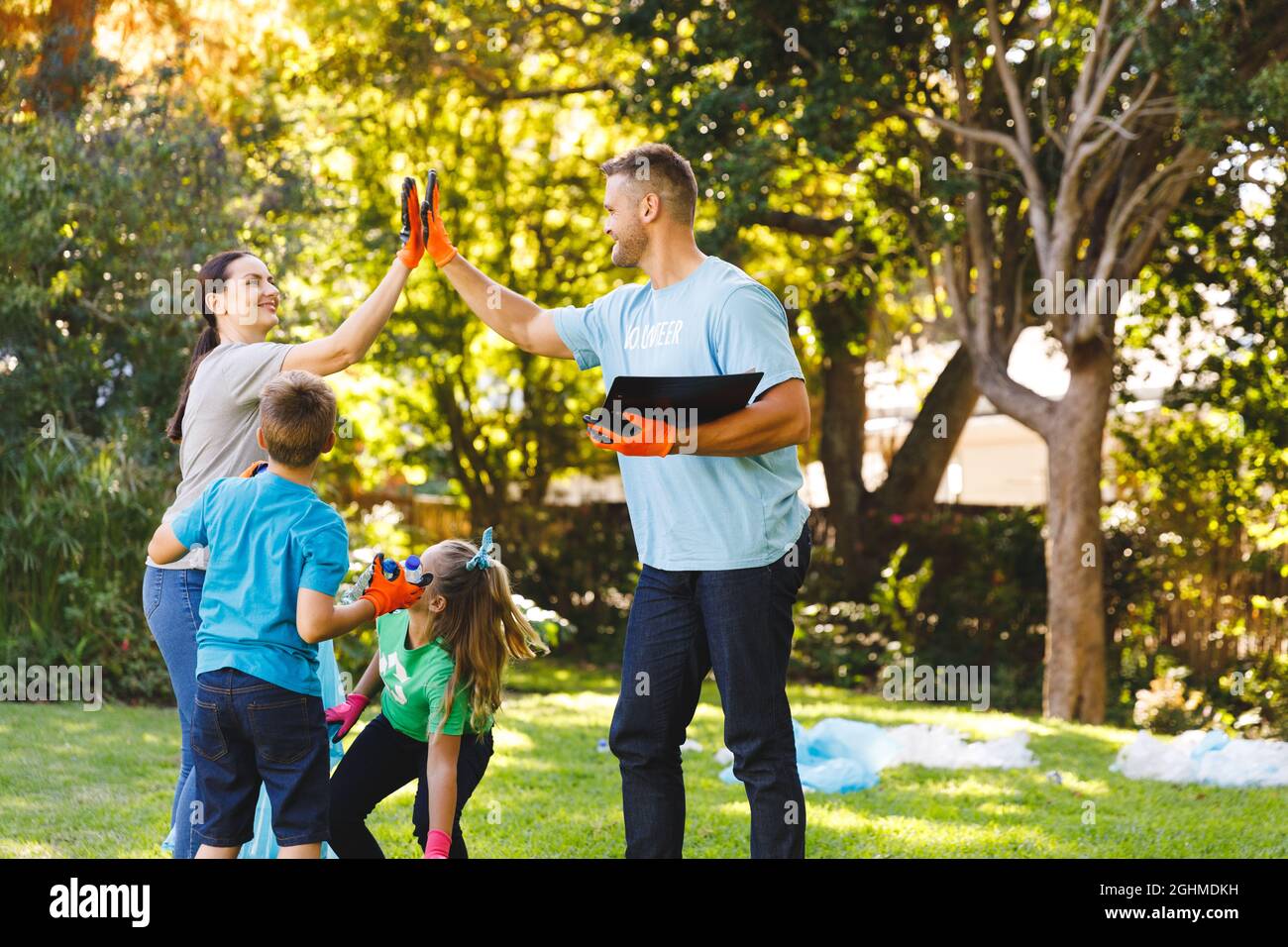 Caucasian parents, son and daughter high fiving, clearing up rubbish in the countryside Stock Photo