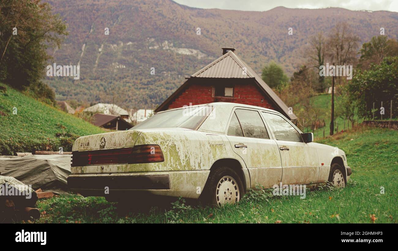 BOVEC, SLOVENIA - Oct 12, 2020: An old weathered dirty white Mercedes Benz on the grassy hill in the countryside in Bovec, Slovenia Stock Photo