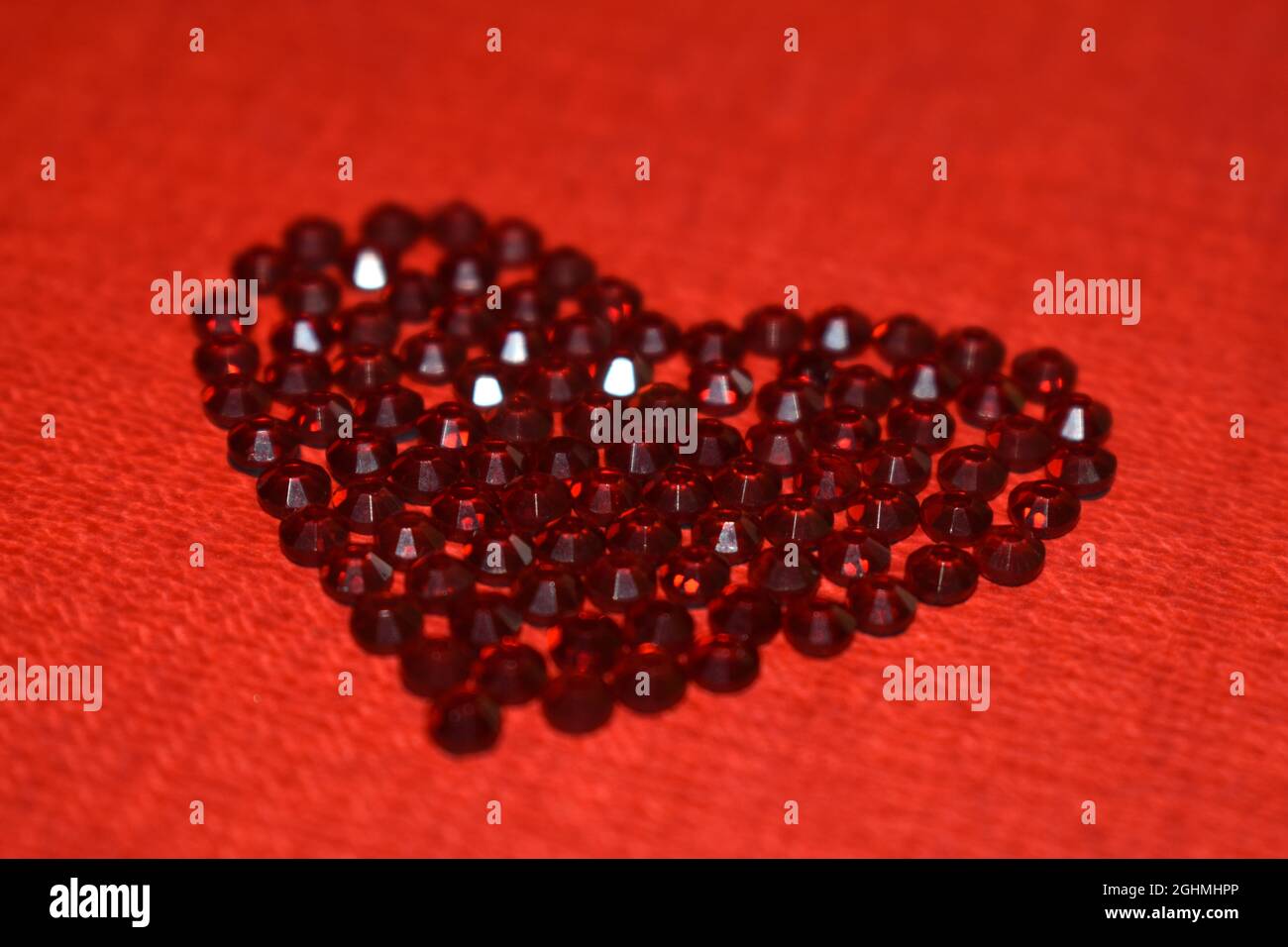 Closeup of the heart-shaped shiny gemstones on the red surface - good
