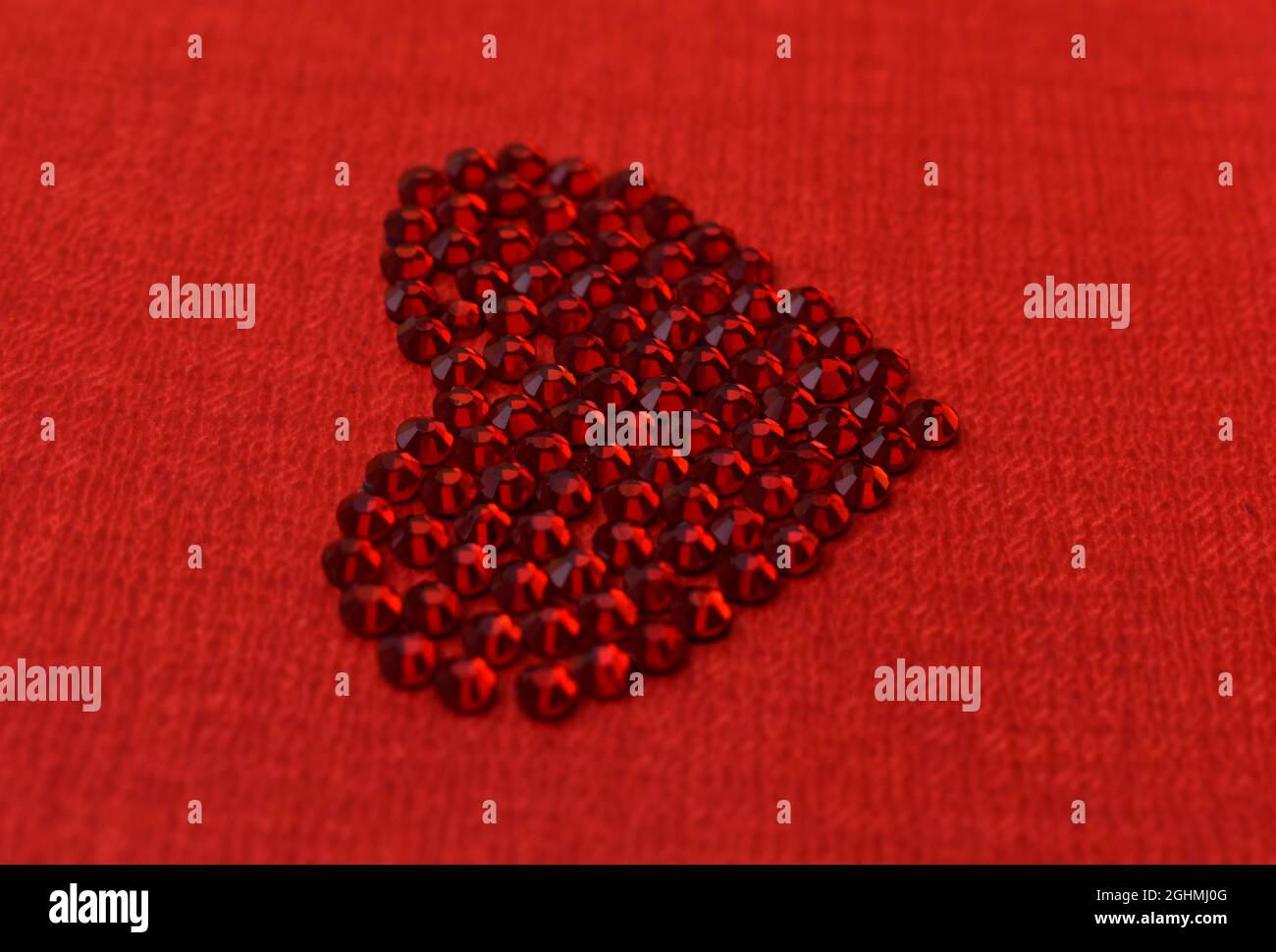 Closeup of the heart-shaped shiny gemstones on the red surface - good