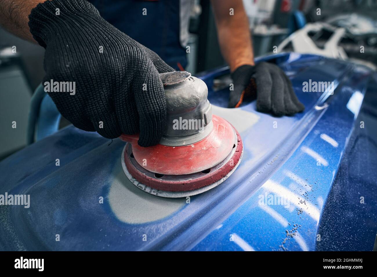 Sander grinding painted bumper in car workshop Stock Photo