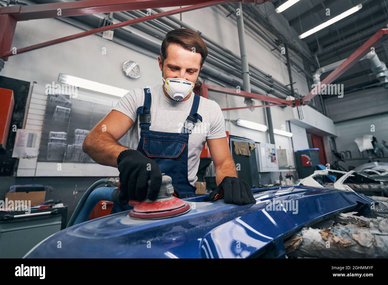 Positive automotive technician grinding automobile body part Stock Photo