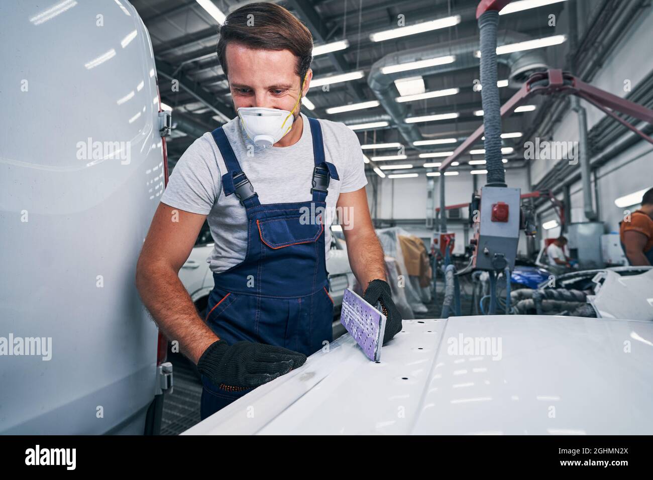 Pleased male holding hand sander looking at his job results Stock Photo