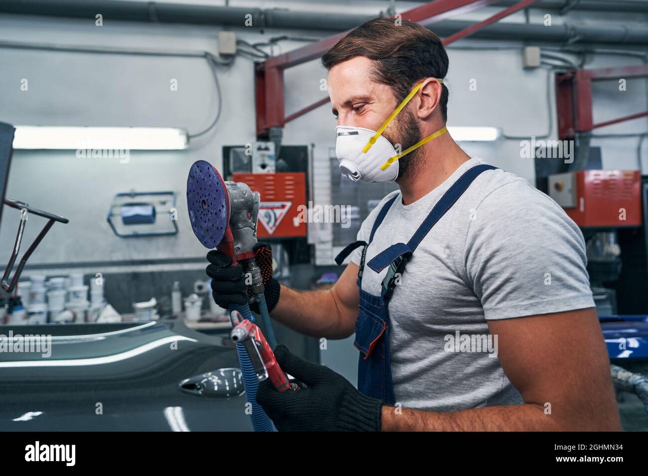 Happy technician holding sander and air blow gun in hands Stock Photo