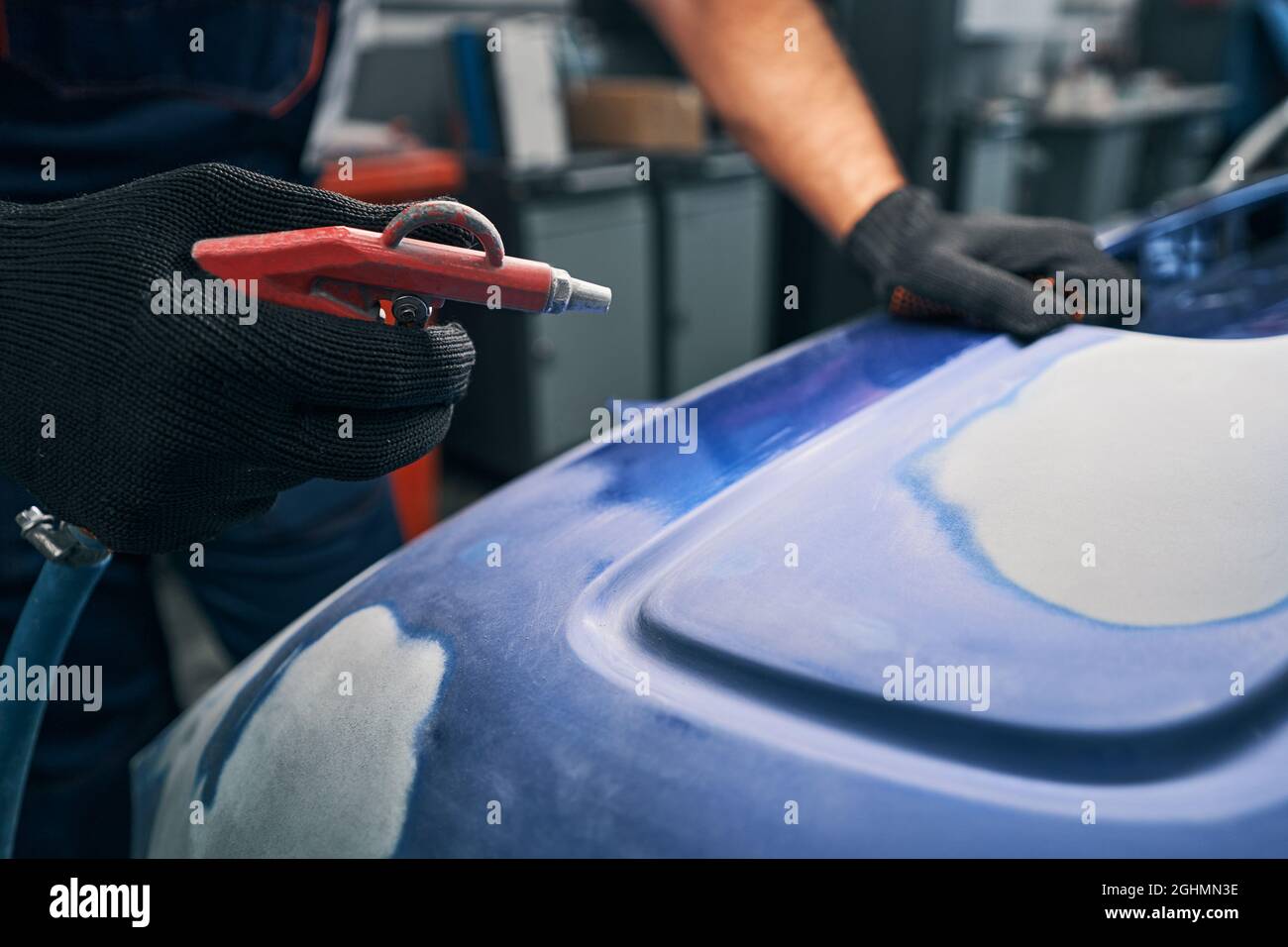Automotive technician pressing on air gun while cleaning car Stock Photo