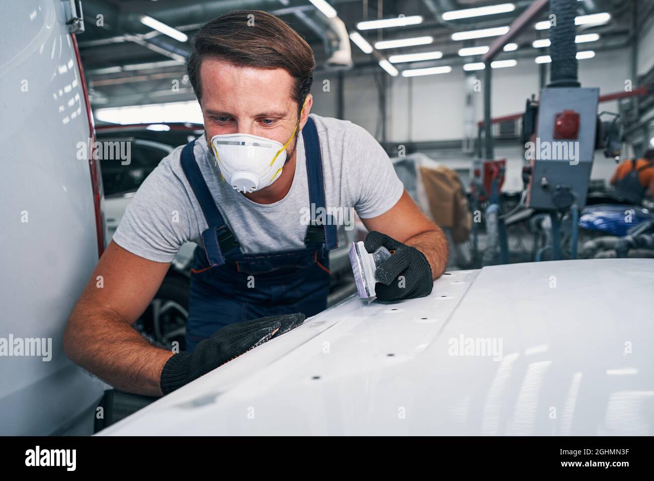 Auto mechanic looking at sanded surface in car repair shop Stock Photo