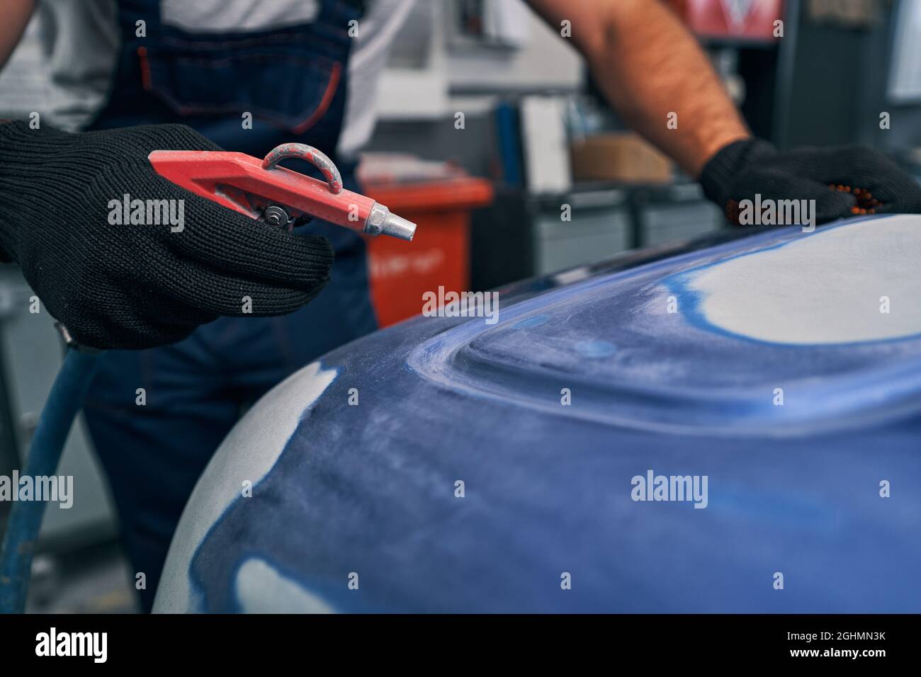 Air blow gun in hand on auto mechanic at work Stock Photo