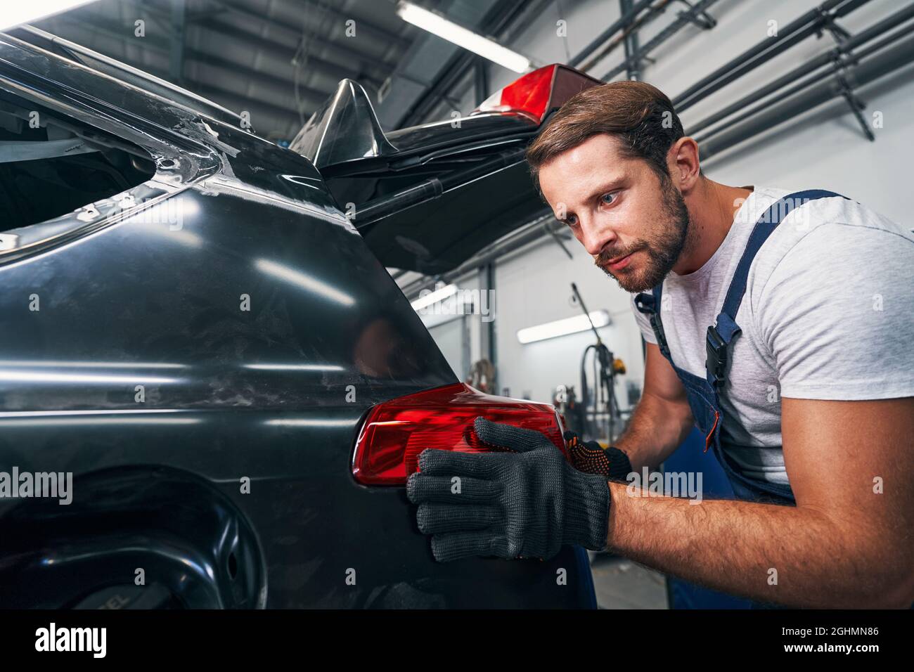 Tachnician is touching rear light of car Stock Photo