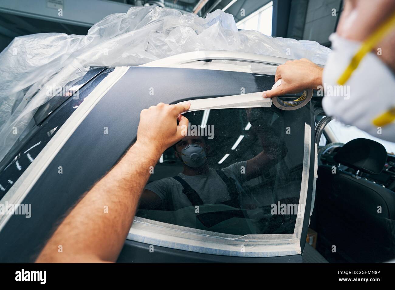 Car service technician sticking duct tape on window Stock Photo