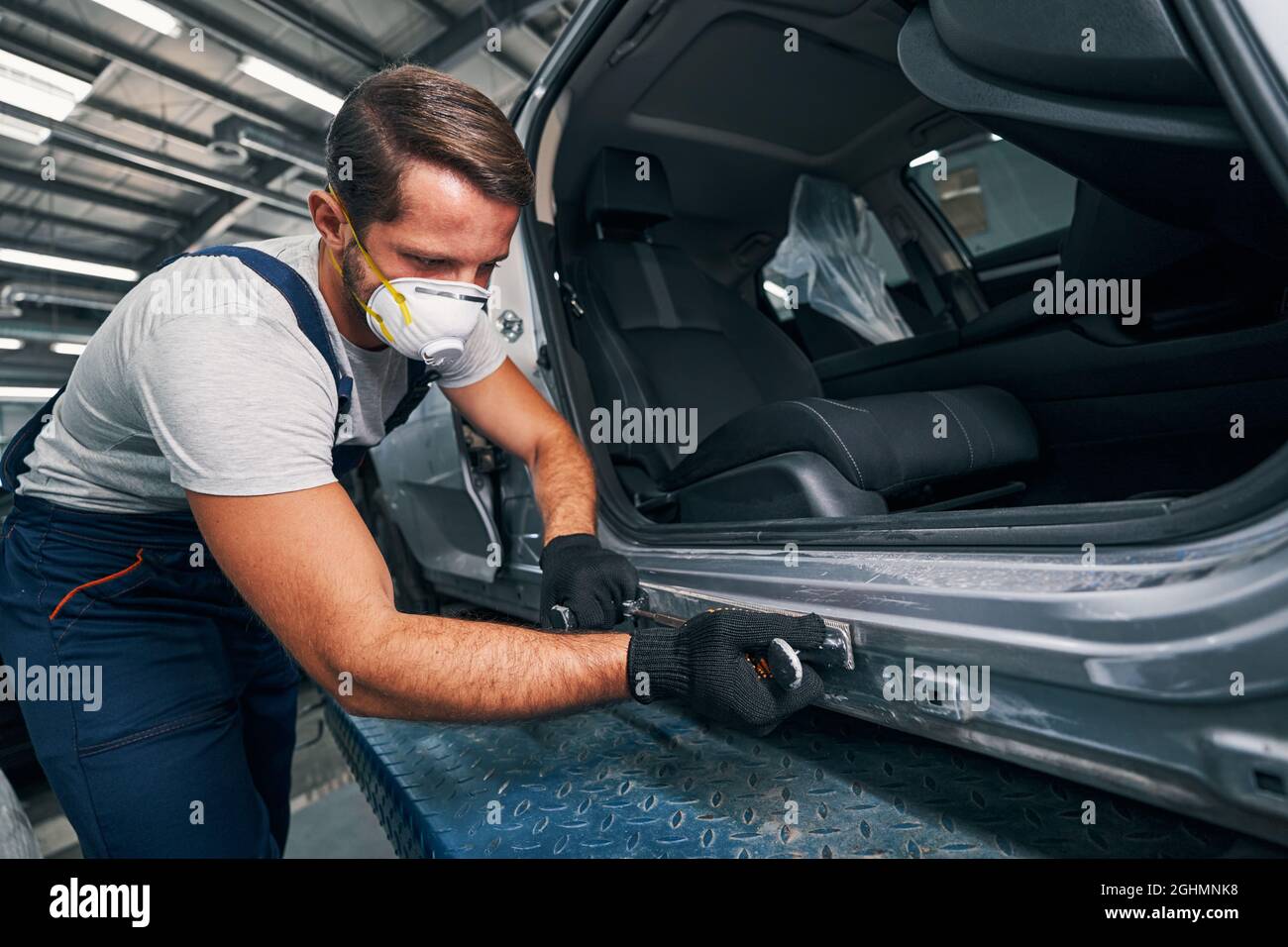 Caucasian repairman placing a metal plate over side panel Stock Photo
