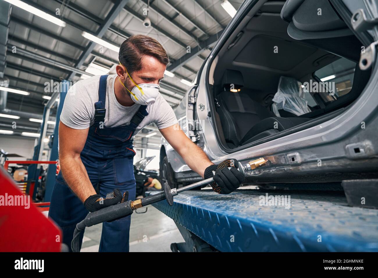 Mechanic removing dents from rear part of car Stock Photo