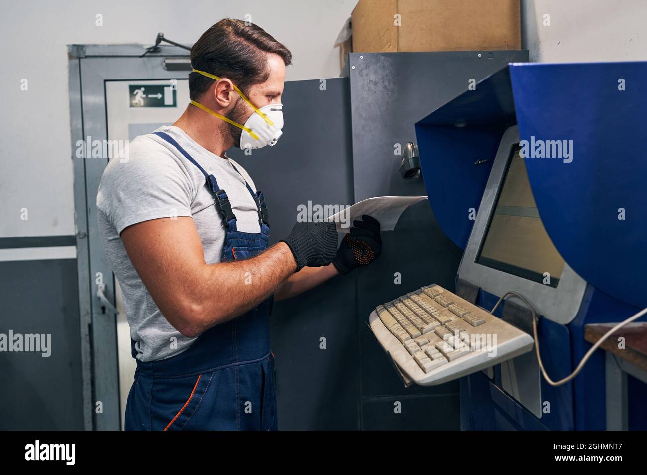 Mechanic reading technical documentation and searching in computer Stock Photo