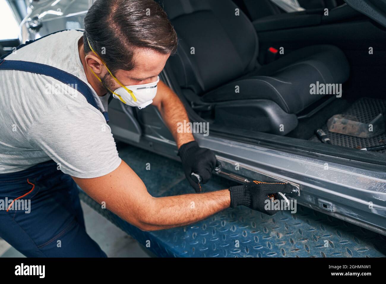 Mechanic pressing peening tool to metal car side panel Stock Photo