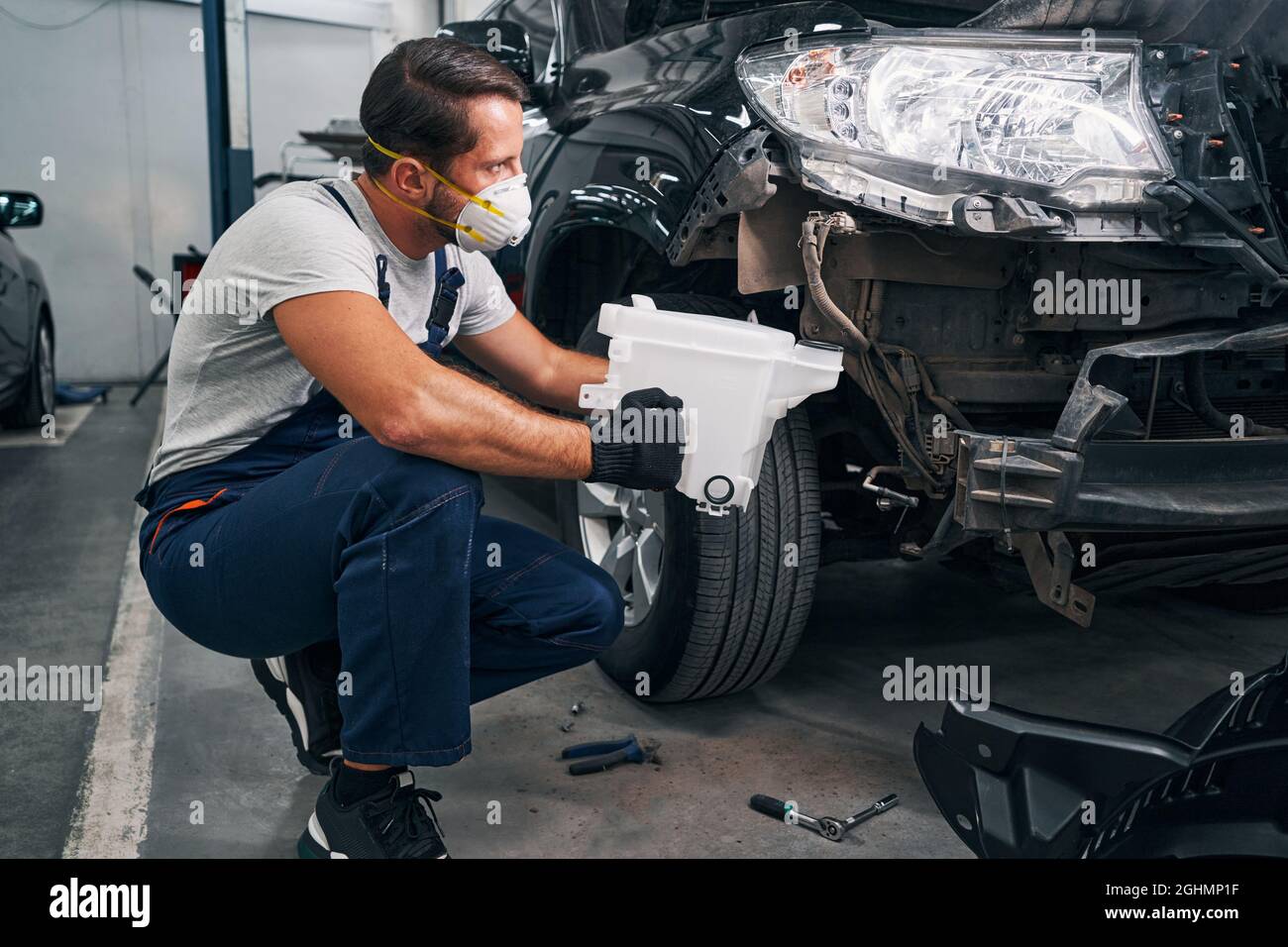 Mechanic is removing washer reservoir from car Stock Photo