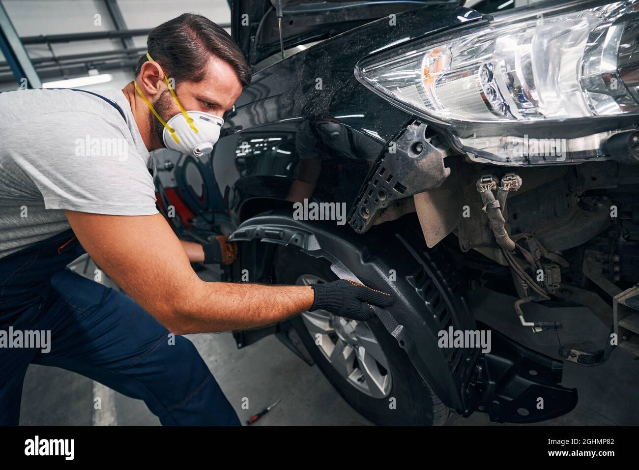 Man pulling out car wheel arch cover Stock Photo