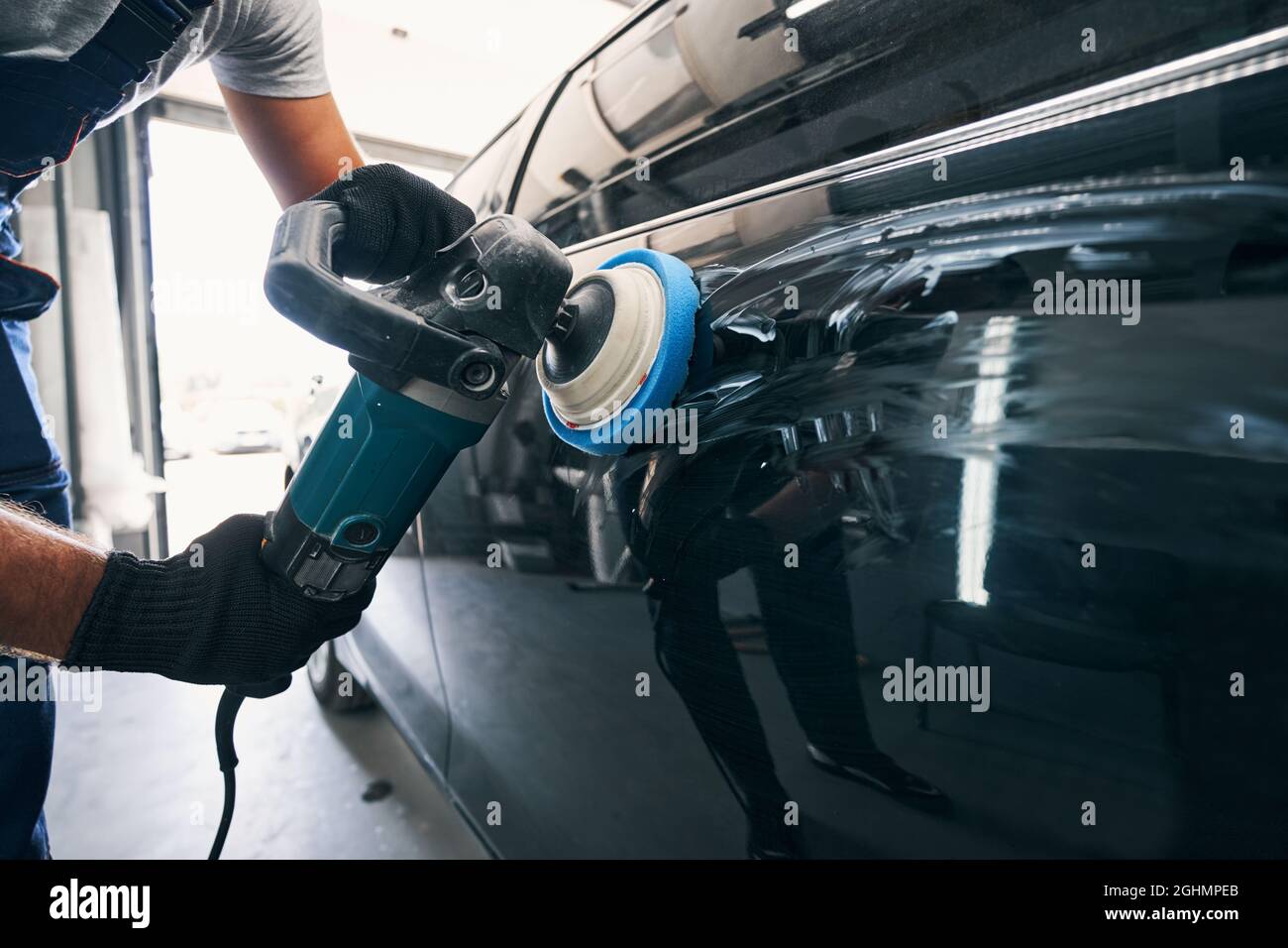 Auto mechanic using polisher with felt pad on car Stock Photo