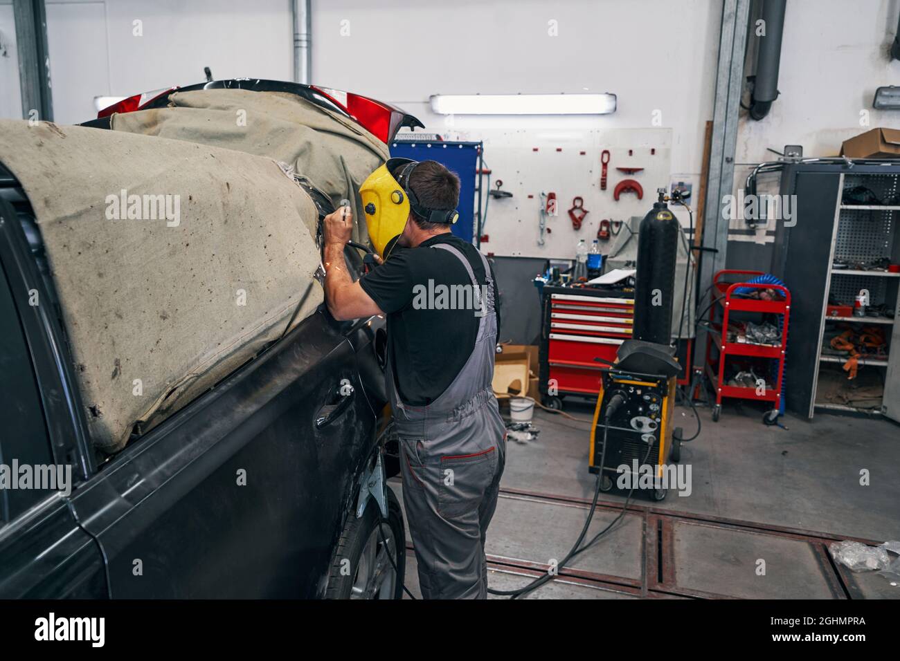 Mechanic welding a part of car under cover Stock Photo