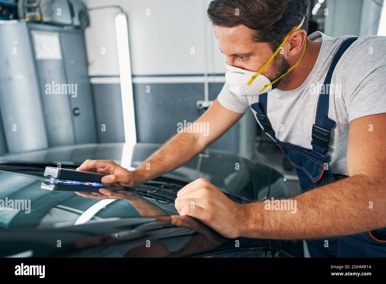 Automotive repairman fixing cracks on windshield with UV-lamp Stock Photo