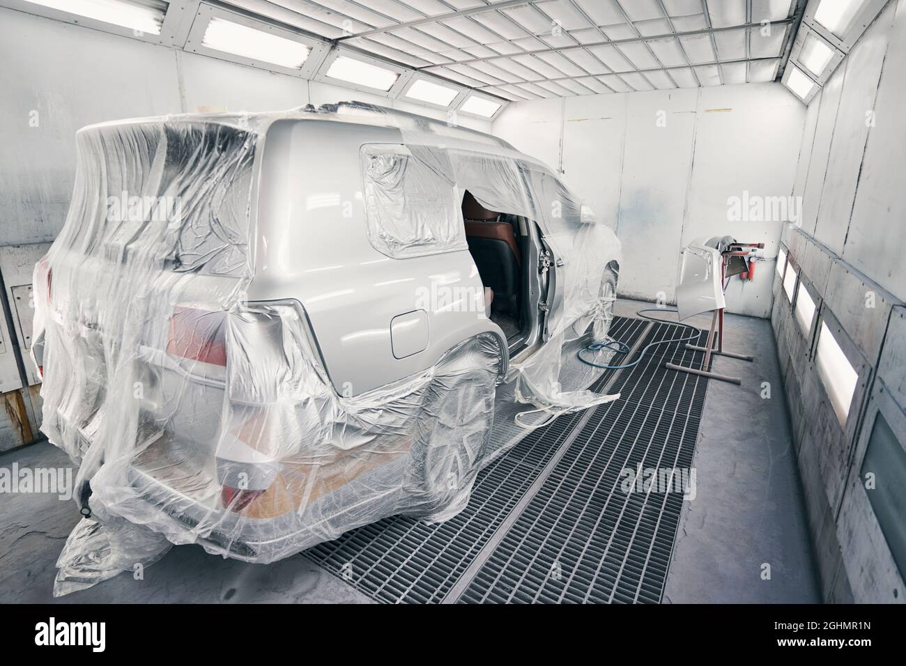 Van covered in film standing in spray booth Stock Photo