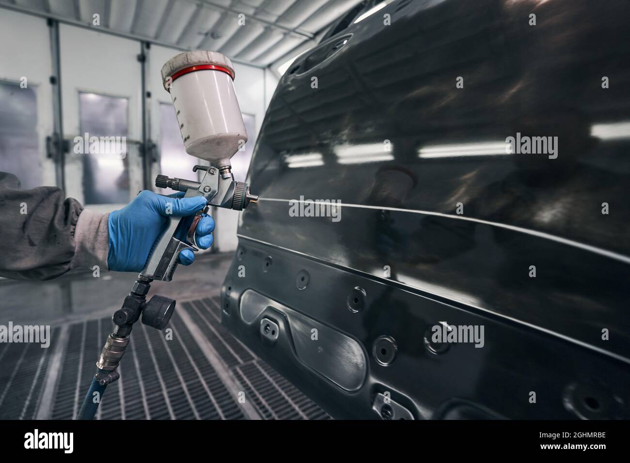 Male activating paint-spraying pistol while working on car Stock Photo