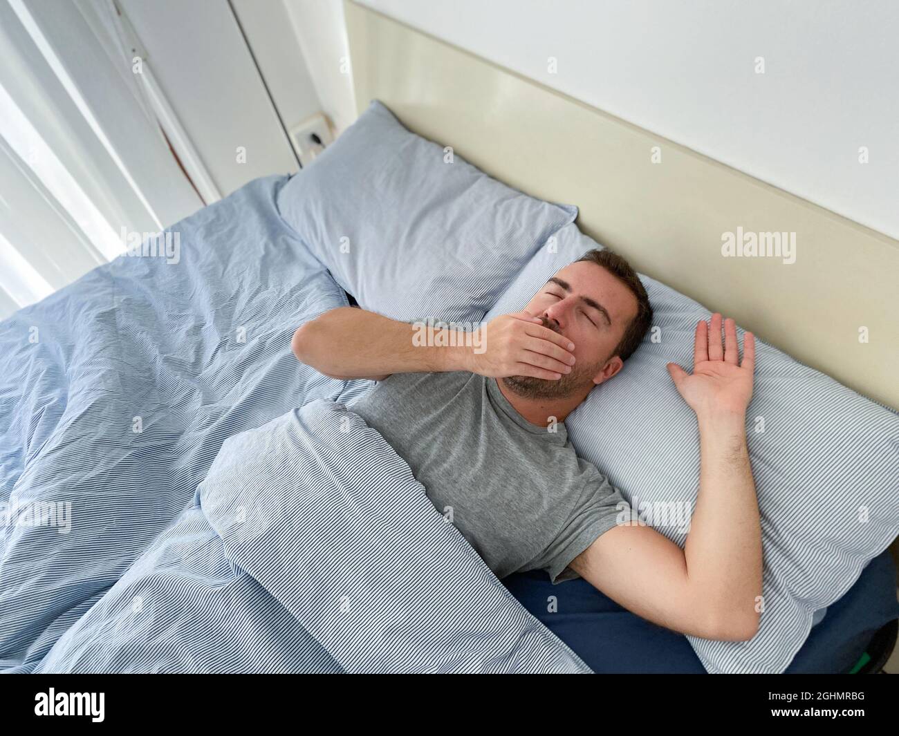 Tired man waking up early in the morning Stock Photo