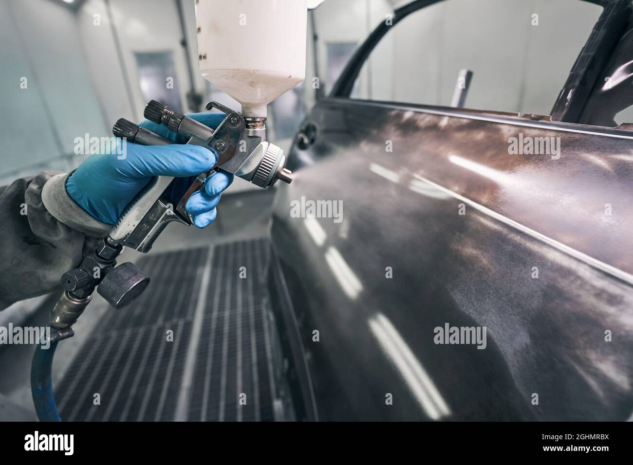 Automobile technician painting auto with spraying gun Stock Photo