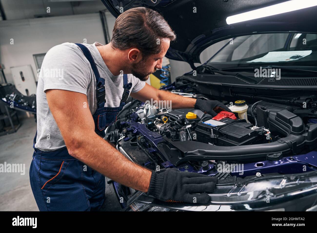 Professional mechanic adjusting red battery under car hood Stock Photo