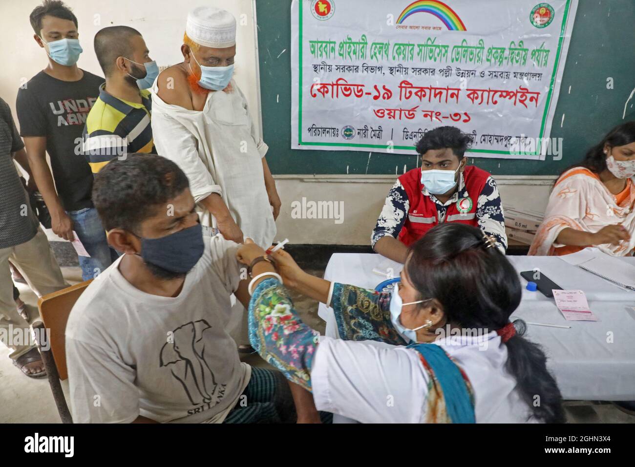 A Person receives The booster dose to avoid the risk of being infected  during  the Corona national mass vaccination campaign at Mohammadpur High School. The program started simultaneously across the country on Tuesday  at 9 am. On September 9, 2021 in Dhaka, Bangladesh. (Photo by Maruf Rahman  / Eyepix Group) Stock Photo