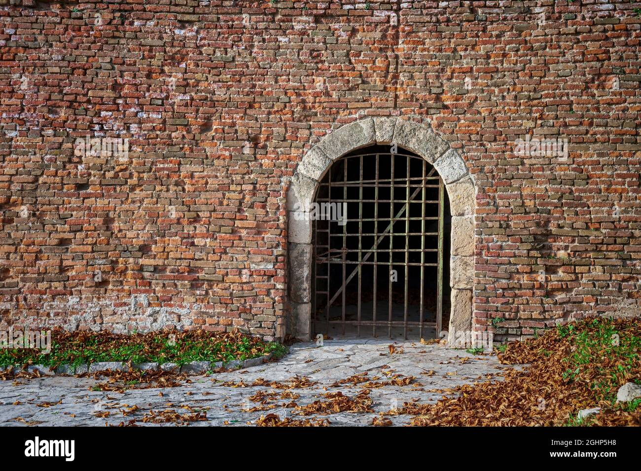 Medieval Fortress Dungeon Door with Iron Bars in Brick Wall Stock Photo