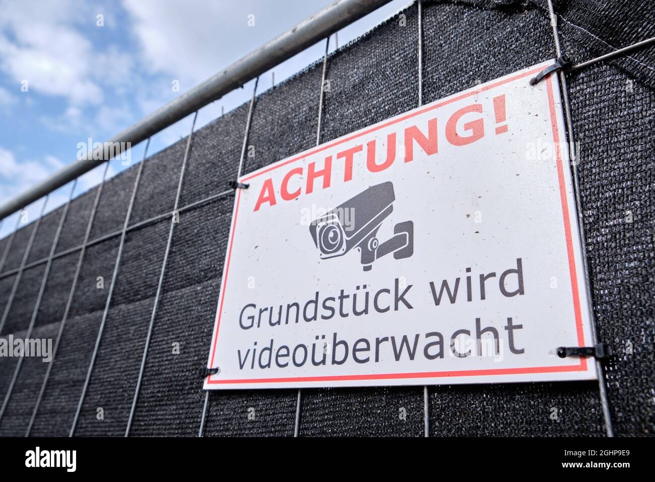 Nuremberg, Germany - August 24, 2021: Close-up of sign at fence of a construction site telling pedestrians Achtung! Grundstück wird videoüberwacht ( W Stock Photo