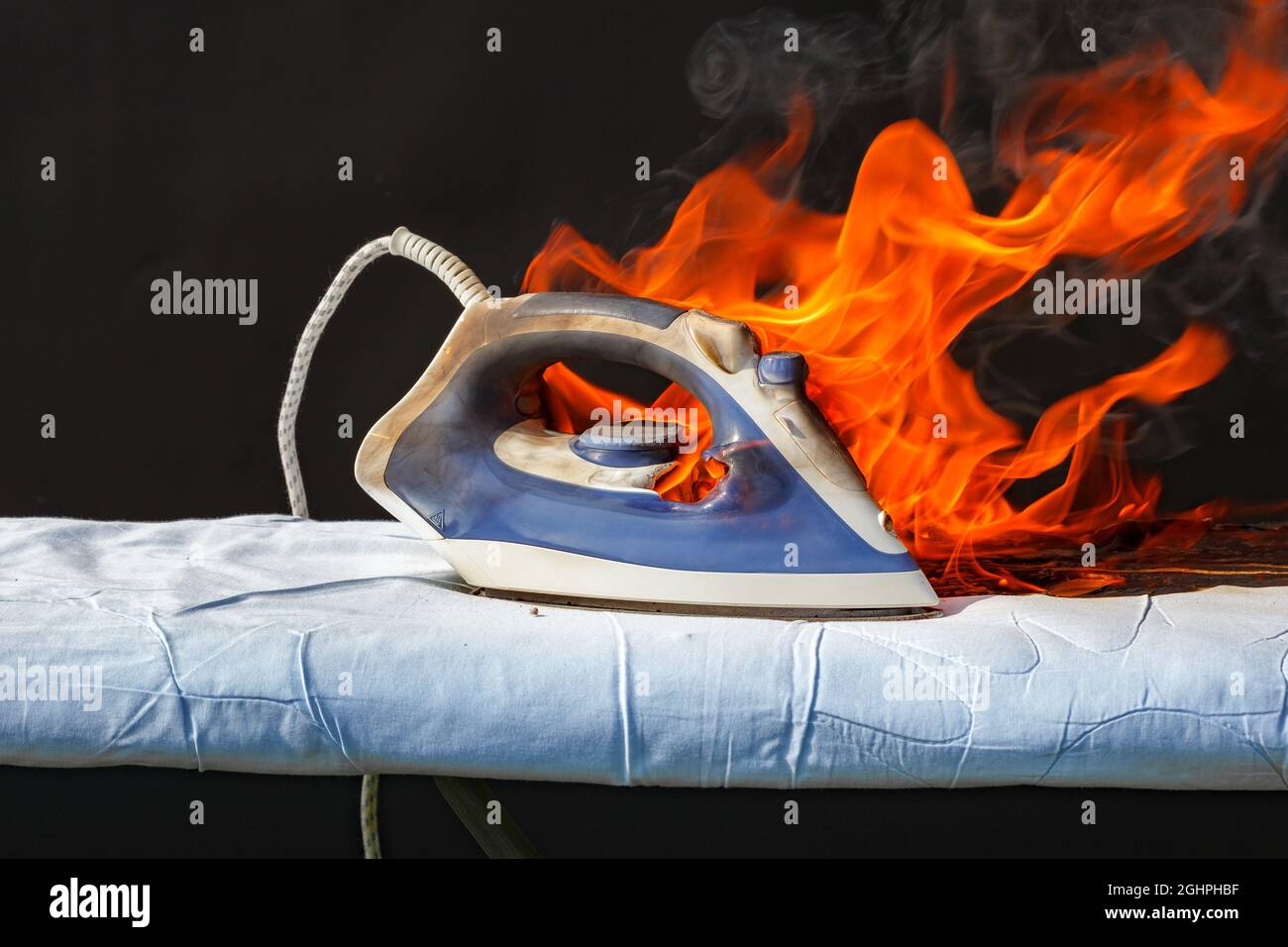 Iron in flames of fire, faulty wiring, cause of fire Stock Photo